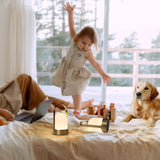 Die fröhliche Kleine hüpft auf dem Bett, neben ihr sind Mama, der Hund und die tragbare Nachtlicht Dawn.